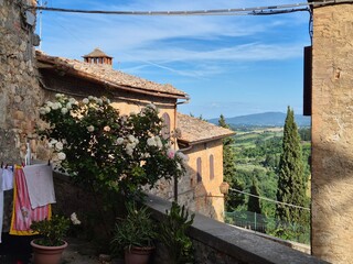 Fototapeta premium Medieval streets of San Gimignano, Tuscany, Italy with lush landscape of green rolling hills in the background