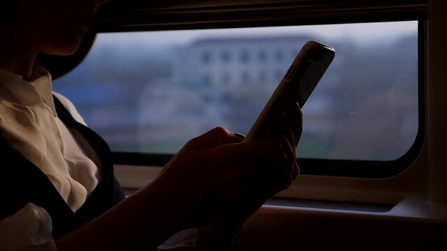 Business woman using smartphone while travelling by high speed train from Shanghai to Beijing, close slow motion shot of mobile device in hands. Blurred backgrounds, rural outdoors sweep past outside