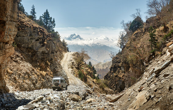 Offroad Car driving on rocky dirt mountain road in Upper Mustang, Nepal against snowy peaks. Extreme adventure travel concept.