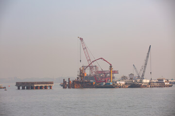 Fototapeta premium Piling cranes on barge hammering a concrete piles into sea - Offshore oil and gas sea construction at port of Mumbai, india