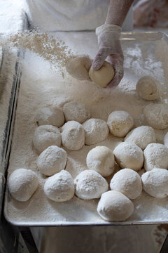 Baker dusting fresh dough balls with flour