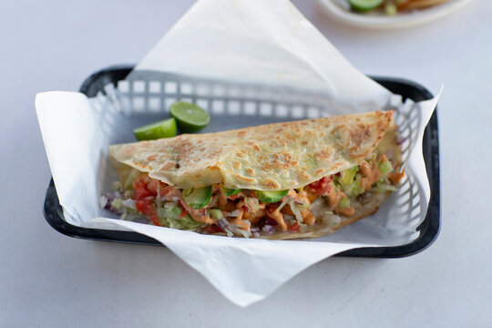 A fresh seafood quesadilla with avocado and lime wedges