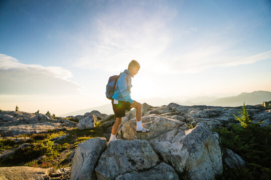 Young boy hiking up a rocky mountain summit