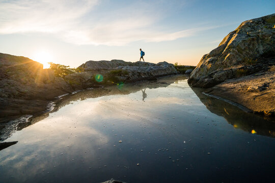 Man with backpack hikes on rocks at sunset