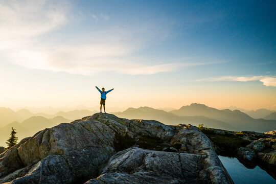 Person celebrating on a rocky mountain summit at sunrise