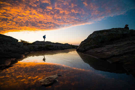 Hiker silhouette on rocks at vibrant sunset