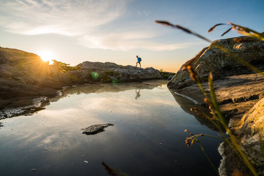 Man hiking on rocks near water at sunset