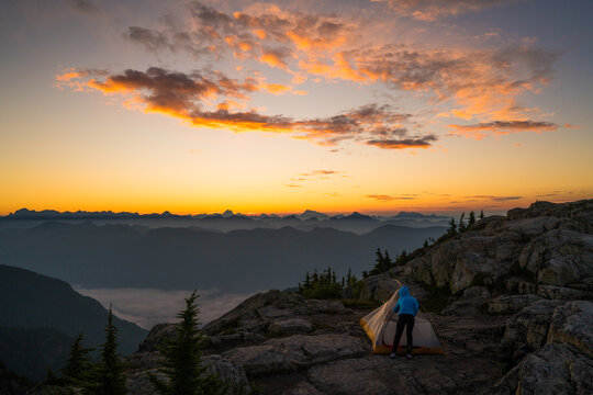 Woman camping on mountain summit at sunrise