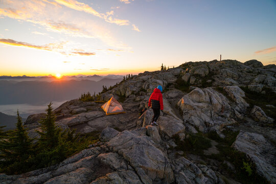 Person exploring a mountain campsite at sunrise