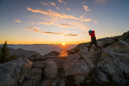 Person leaping between rocks at mountain sunrise