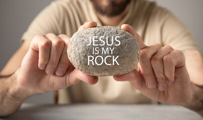 Obraz premium Man showing Jesus Is My Rock message on rock.