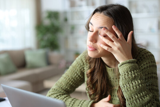 Woman at home scratching itchy eye with her hand