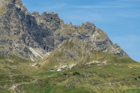 Summit Aries stone with Widdersteinh&uuml;tte and red flowered colored meadows, hiking place in the alps of Bregenzerwald, with rocky mountains and steep, stony slopes on a sunny day with veil clouds.