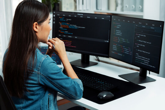 Young Asian IT developer looking online information on pc for beautiful pose with coding program data of website application, wearing jeans shirt. surround by safety analysis two screens. Stratagem.
