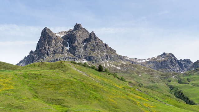 Summit Aries stone and red flowered colored meadows and K&ouml;rber lake in the alps of Bregenzerwald, with rocky mountains and steep, stony slopes on a sunny day with veil clouds.