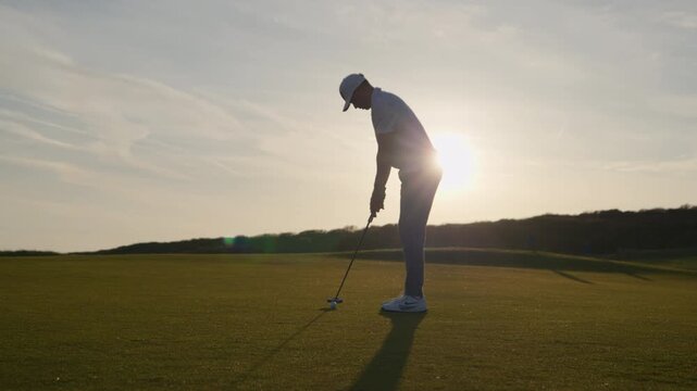 Golfer misses putt and looks disappointed, sunset golf course
