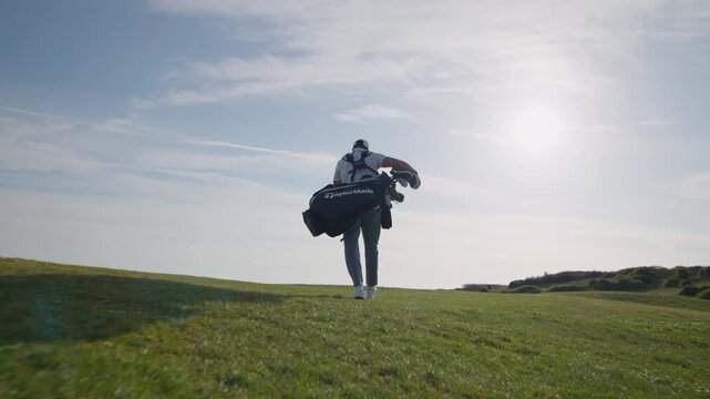 Low angle slomo shot of golfer walking golf course