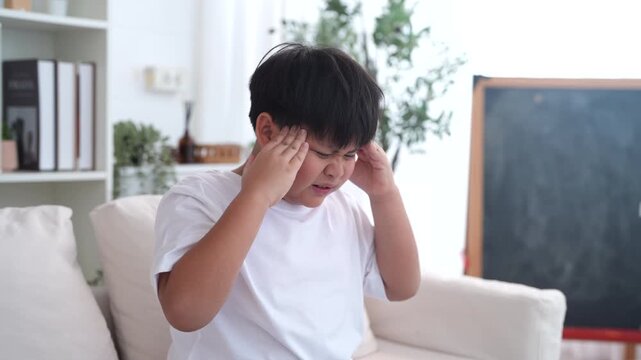 Mental health, Unhappy asian boy holding head with hands showing sad expression, Concept of child health problem, headache pain, emotional stress, childhood frustration and psychological care support