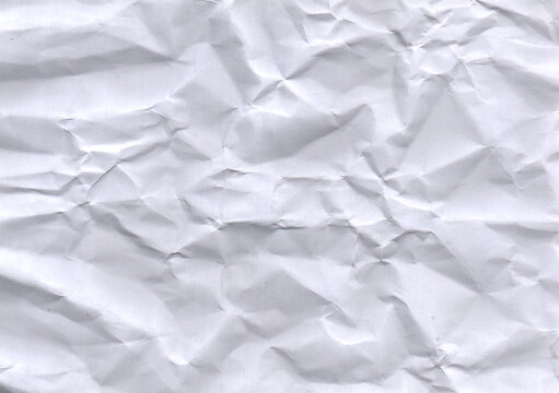 Crumpled white paper texture displays a chaotic arrangement of folds and creases creating a distressed surface wrinkled