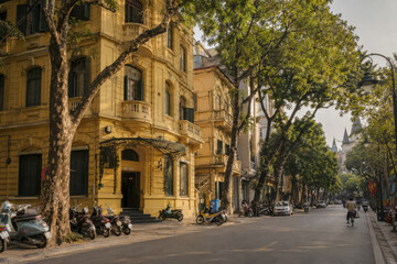 Fototapeta premium French colonial corner building on a quiet tree-lined Hanoi street.generative AI