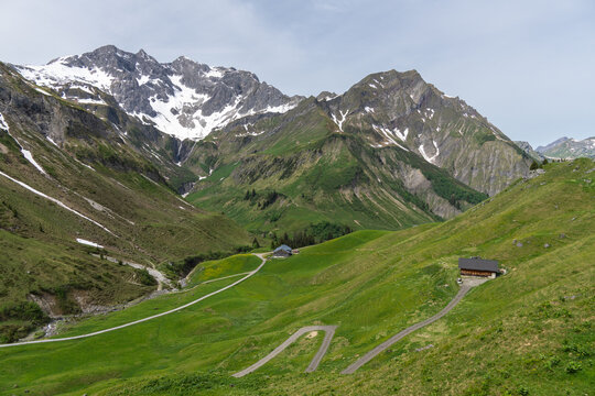 panorama with wooden holiday house on spring colored meadows. spring in forested mountains with foggy sky. hiking area in Bregenz forest, Vorarlberg, Austria. holiday destination for hike and skiing