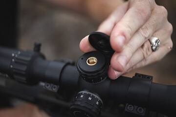 Hands adjusting rifle scope windage turret © Dewald