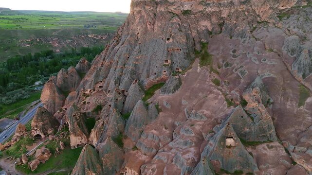 drone view of Selime Cathedral ancient rock-cut complex overlooking a green valley. Historic Christian troglodyte architecture and mountain wilderness in Turkey
