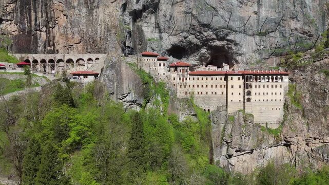 drone shot of Sumela Monastery carved into the rugged mountain cliffs of Altindere Valley. Iconic archaeological landmark, forest landscape and cultural heritage tourism in Turkey.