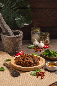 sambal pecel served on a table with a base and served on a wooden plate with a spoon,leaves,chilies,peanuts and spices as decoration.