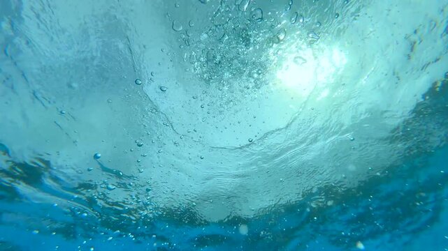 Underwater view captures glistening blue water of a swimming pool. Tranquil leisure and summer relaxation concept. Light ripples dance across the surface, inviting swimmers to enjoy a refreshing dip