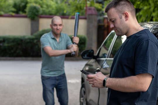 Parking lot stress .A psychotic driver aggressively approaches another driver with a baseball bat.