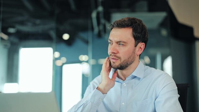Close-up of exhausted businessman or IT specialist experiencing acute toothache or cavity problem at computer. Overworked corporate manager or freelance worker needing dental help during workday
