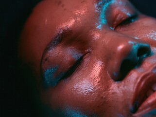 Fototapeta premium Extreme close-up of a Black woman with glowing skin under red light therapy for wellness and high-tech skincare advertising