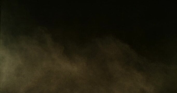 Slow motion dust or sand cloud drifting through the air on a black background. Cinematic particle explosion effect ideal for overlays, compositing, visual effects, motion graphics and VFX projects.