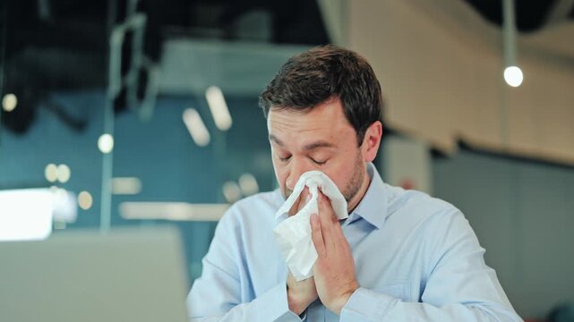 Close-up of sick corporate worker or freelance designer suffering from runny nose, allergy symptom or seasonal virus at laptop. Exhausted manager or IT specialist feeling bad health problem at desk