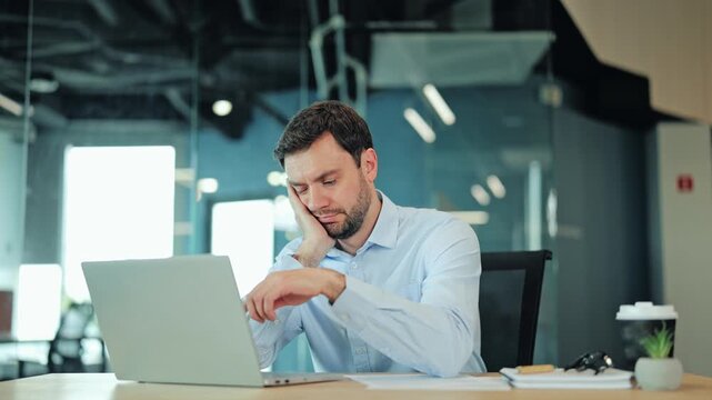 Close-up of exhausted corporate manager or IT specialist feeling sleepy, tired or unmotivated at computer. Lazy employee, bored worker or freelance designer wasting time during dull routine task