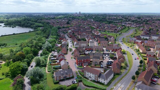 Low aerial view of modern residential suburb housing in Ely with the historic Ely Cathedral towering in the distance, Cambridgeshire, UK.