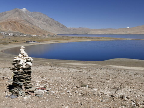 Cairn made of stones in front of tso moriri lake and himalayan mountains in Ladakh, near Korzok. Scenic landscape in summer