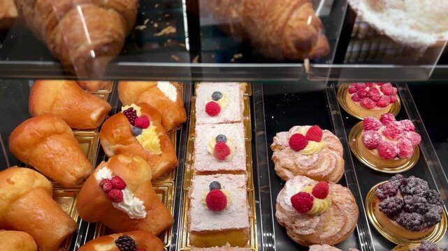 Assorted Italian pastries including baba and cream cakes with berries displayed in traditional Amalfi coast bakery showcase	