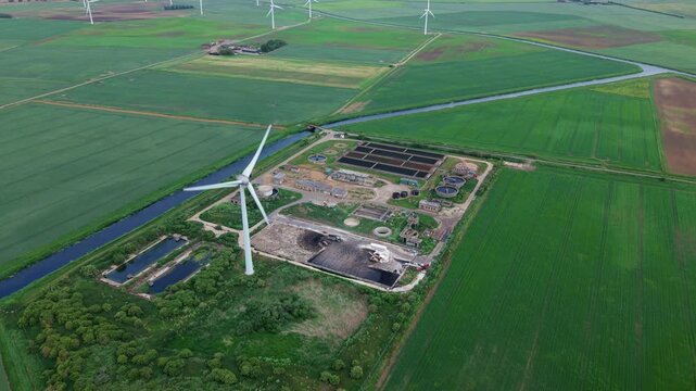 Aerial view of Wastewater Treatment Works featuring a single on-site wind turbine for renewable power, Cambridgeshire, UK