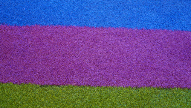Colorful artificial turf samples in blue, purple, and green stripes.