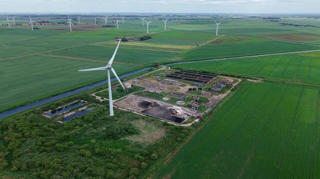 Aerial view of Wastewater Treatment Works featuring a single on-site wind turbine for renewable power, Cambridgeshire, UK
