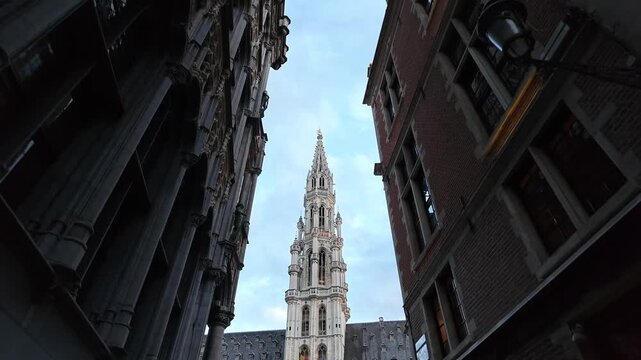 Grand Place Belgium sunset. Low-angle 4K video looking up at the majestic Gothic tower of the Brussels Town Hall between historic guild houses in the famous Grand Place market square.