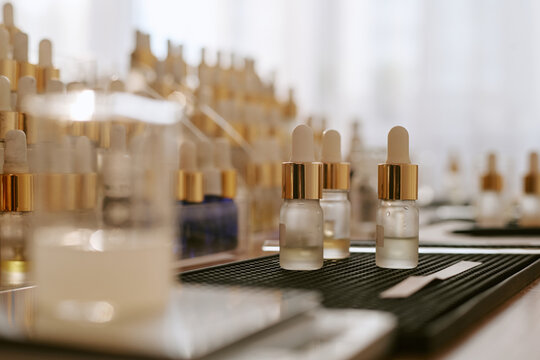 Close up of cosmetic serum bottles standing in production line, showcasing skincare packaging and beauty product manufacturing. Ideal for cosmetics branding, retail, ecommerce