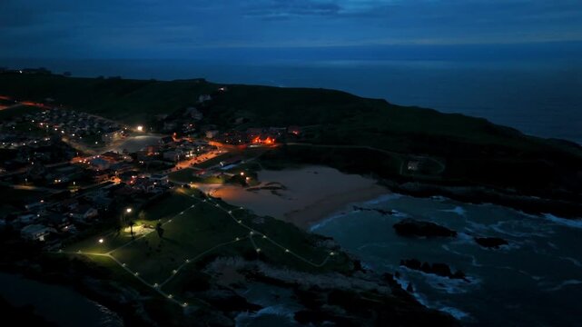 Drone view of a coastal village with a sheltered sandy cove at twilight in Santander Spain