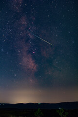 Fototapeta premium Constellation and Milky Way stars on a dark countryside skies with landscape silhouettes.
