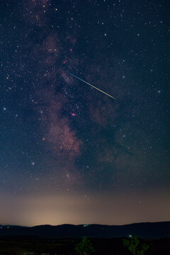 Constellation and Milky Way stars on a dark countryside skies with landscape silhouettes.
