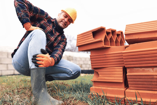 Construction worker having a accident and injured knee and leg on a construction site outdoors.