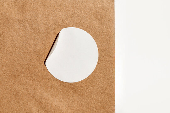 Blank white sticker peeling on brown paper surface