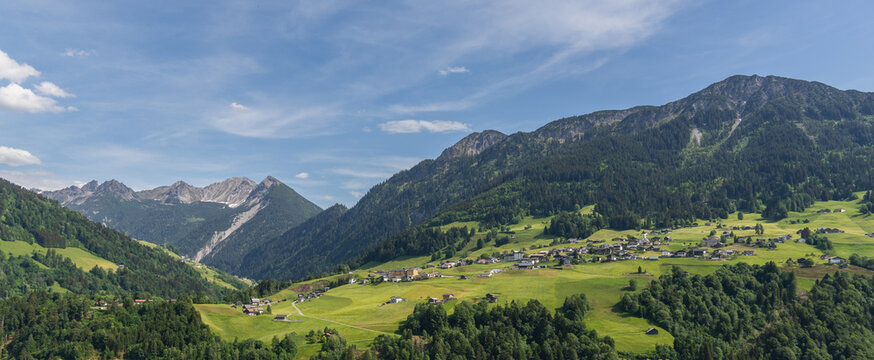little village on a plateau in Grosswalsertal, in the middle of the mountains from Bregenzerwald. Panoramic view from an Austrian Alp to the spring-colored mountain